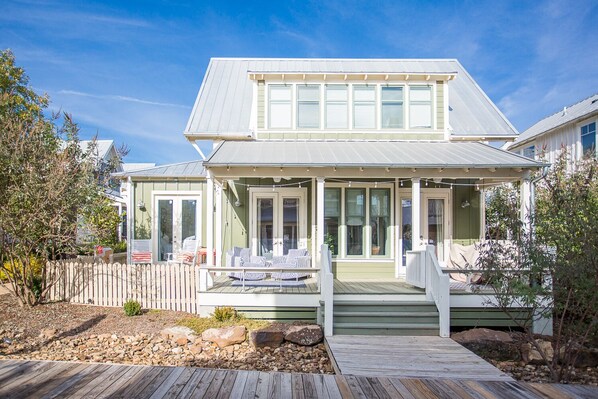 A two-story house with a covered porch, a deck, and a fenced yard.