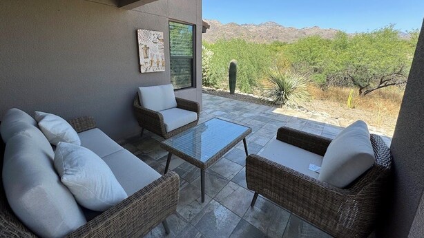 A patio with wicker furniture and a glass table, overlooking a desert landscape with cacti and mountains. - Best VIEWS & largest Extended Patio in the entire community of The Greens (Tucson)