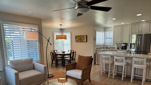 A modern kitchen with white cabinets, a stainless steel refrigerator, and a dining area with a round table and chairs. - Best VIEWS & largest Extended Patio in the entire community of The Greens (Tucson)
