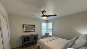A bedroom with a bed, a ceiling fan, a window with blinds, a bedside table, and a lamp. - Best VIEWS & largest Extended Patio in the entire community of The Greens (Tucson)