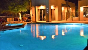 Ein Schwimmbecken mit einem modernen Gebäude im Hintergrund, einem überdachten Sitzbereich und einem verschlossenen Eingang.