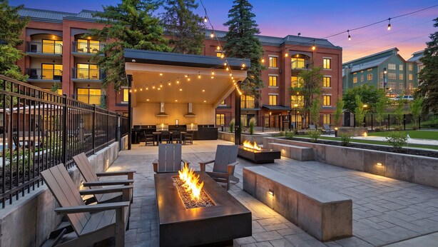 A courtyard with outdoor seating, a fire feature, and a covered area with string lights.