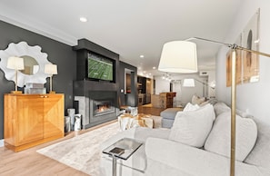 Cozy up by the fireplace in this stylish living room, featuring a comfortable sofa and a large TV.