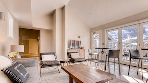 Relax in a spacious living area with a sofa, loveseat, and coffee table, perfect for unwinding with a view of the surrounding landscape.