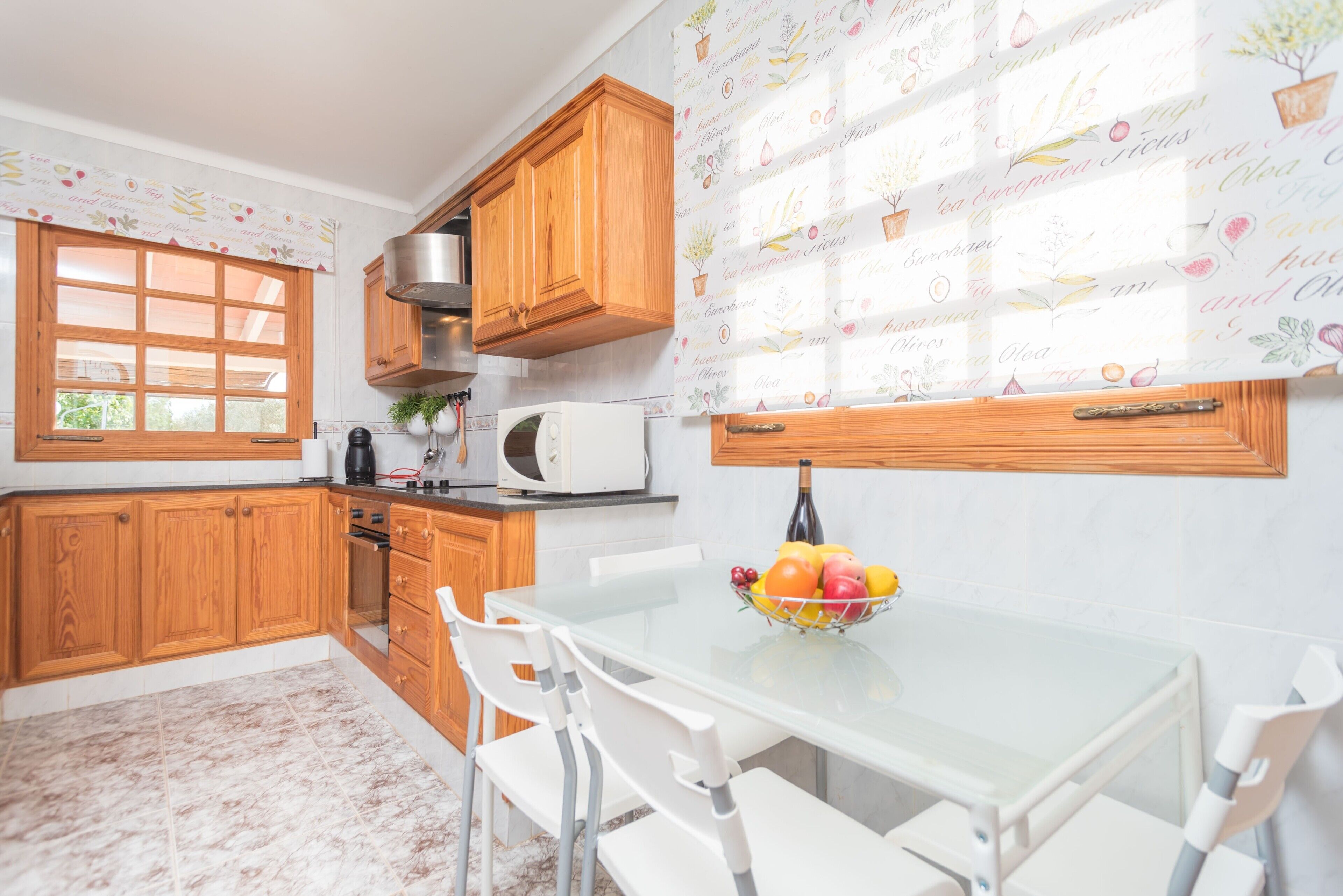 A kitchen with wooden cabinets, a microwave, a sink, and a dining table with chairs.