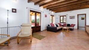 Un salon spacieux avec un plafond haut, un ensemble de canapés, une chaise en bois et un radiateur.