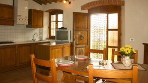 Une cuisine avec des meubles de rangement en bois, un pare-feu en carrelage, une cuisinière, un évier et une table à manger avec des chaises.
