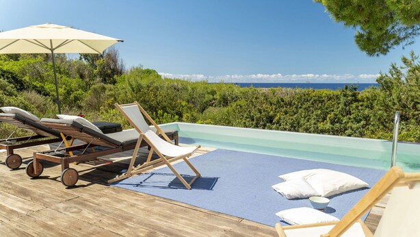 Zona de piscina con sillas de descanso y vista al mar.