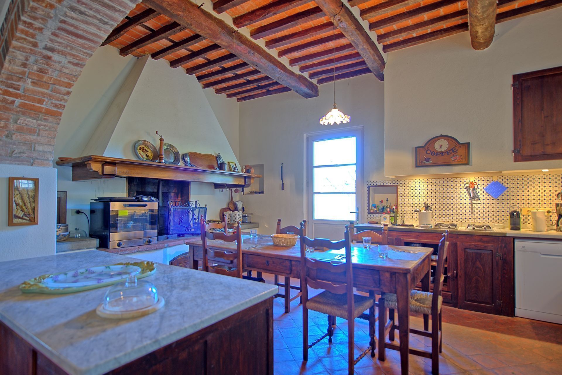 Una cocina rústica con vigas de madera a la vista, una pared de ladrillo y un ventanal amplio.