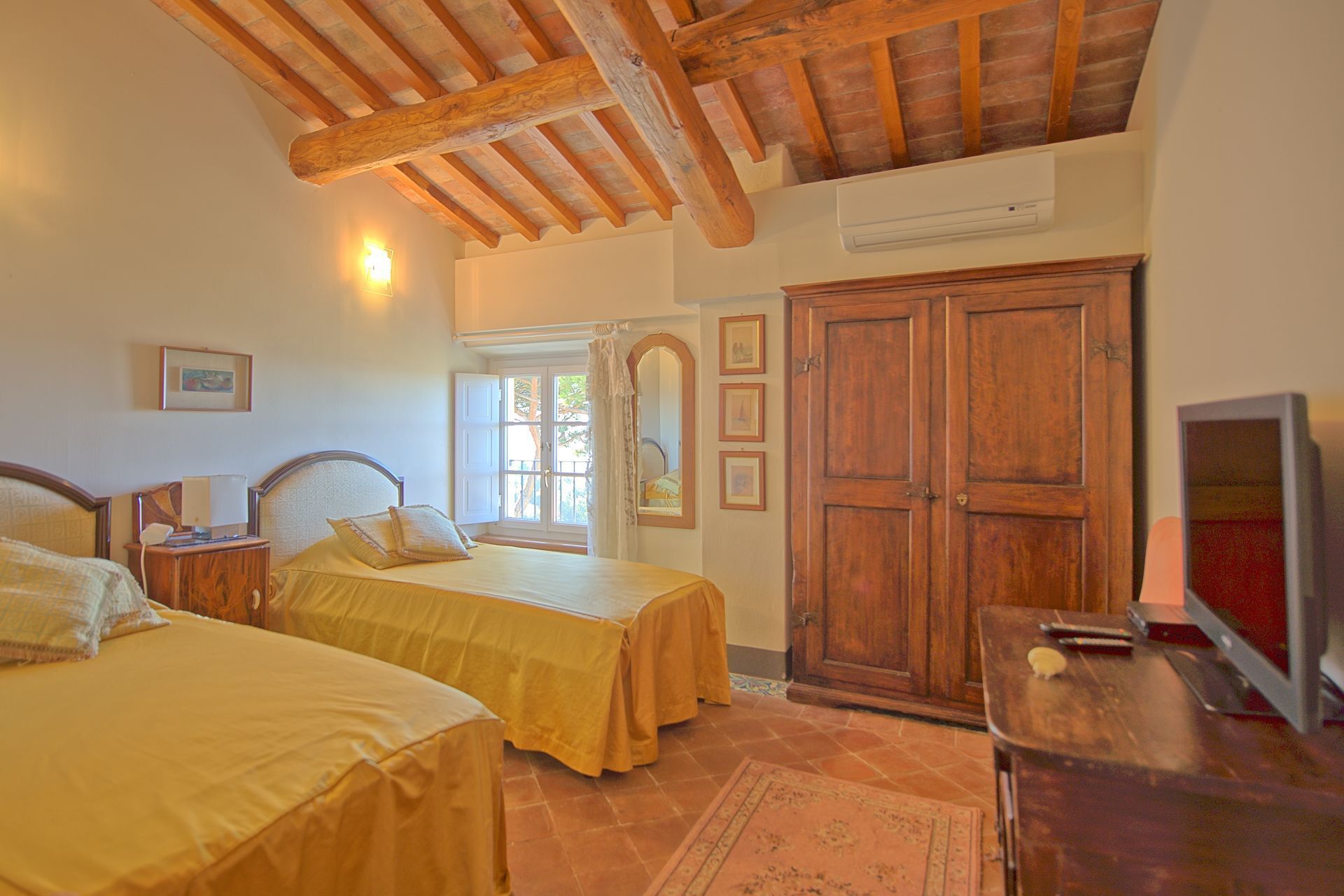 A bedroom with two beds, wooden beams, a wardrobe, and a television.