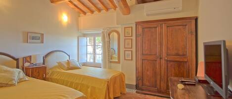 A bedroom with two beds, wooden beams, a wardrobe, and a television.