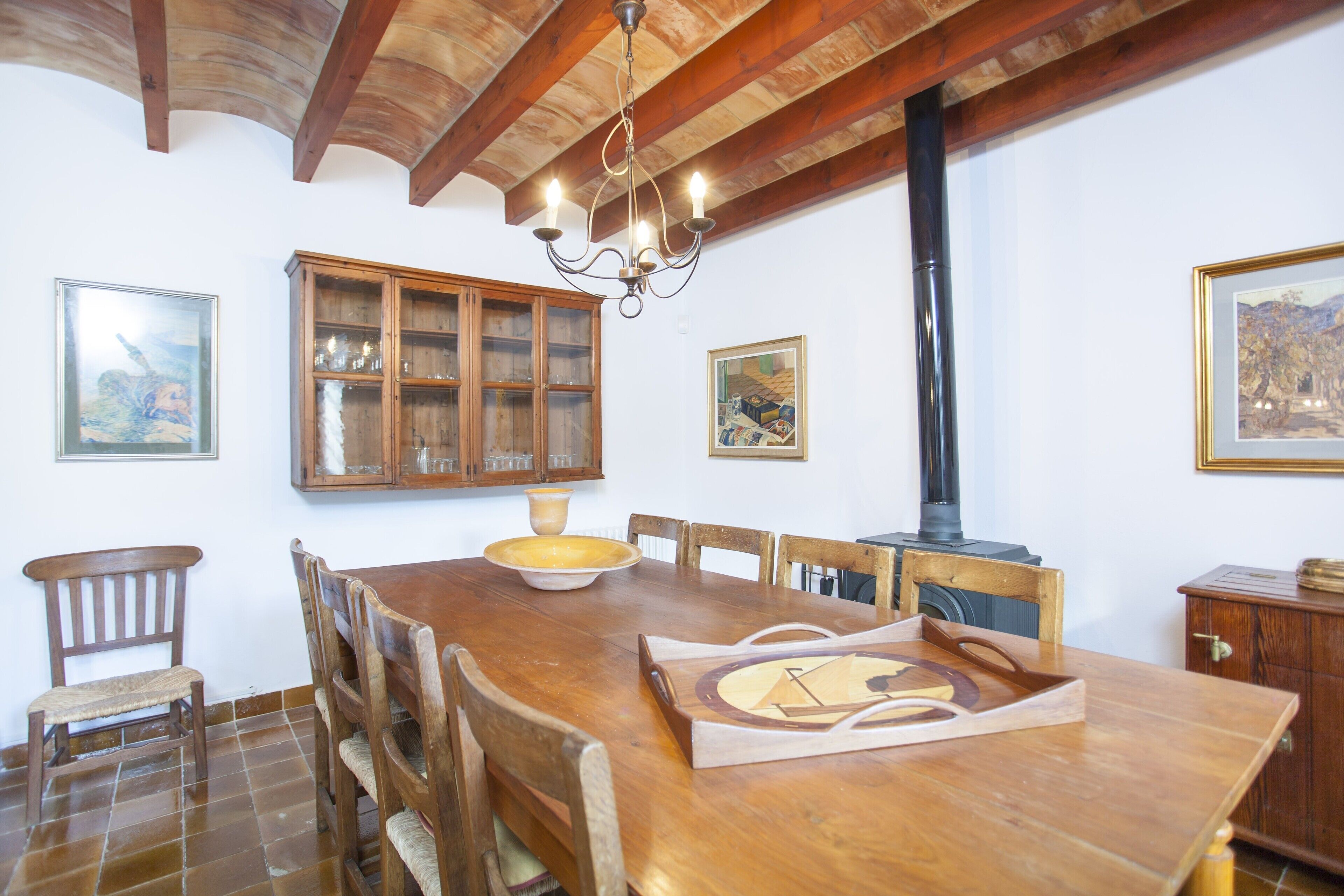 Une table à manger en bois, des chaises, un lustre et un buffet aux portes vitrées.