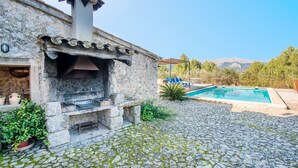 A stone building with a fireplace, a pool, and a mountainous backdrop. - CAN GUILLO - Villa with private pool in Pollensa. Free WiFi (Pollensa / Pollença)
