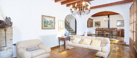 A spacious living room with a wooden ceiling, a large wooden table, and a beige sofa.