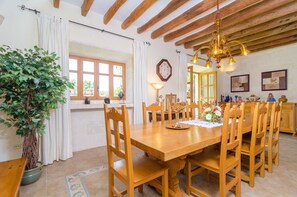 Un coin repas avec une table et des chaises en bois, un lustre et une plante en pot.
