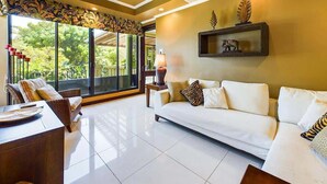 A spacious living room with a white sofa, a dining table, and a ceiling fan.