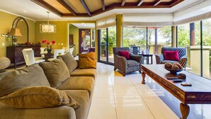 A spacious living room with a large sofa, a coffee table, and patterned armchairs.