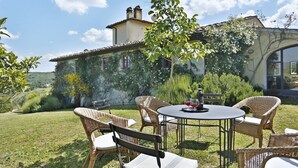 An outdoor seating area with wicker chairs and a round table, set against a backdrop of a house with a garden and a clear sky. - Wonderful private villa with WIFI, private pool, TV, terrace and panoramic view, close to Florence (Torre A Cona)