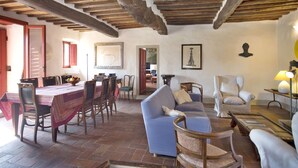 A rustic interior with exposed wooden beams, a dining area with a table and chairs, a blue sofa, and a white armchair. - Wonderful private villa with WIFI, private pool, TV, terrace and panoramic view, close to Florence (Torre A Cona)