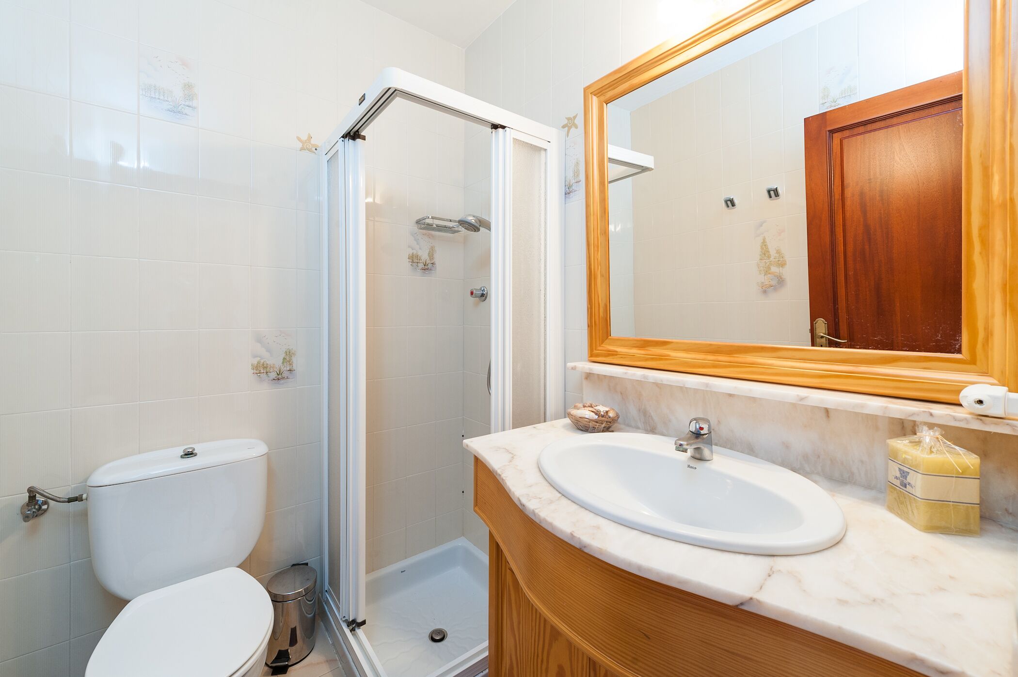 Un baño con inodoro, ducha, lavamanos y espejo.
