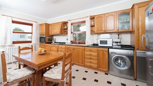 Une cuisine moderne avec des meubles en bois, une table à manger avec des chaises, un lave-linge et un réfrigérateur.
