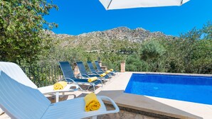A poolside area with lounge chairs and a pool, surrounded by trees and mountains. - SA TARONGERA - Villa with private pool in ANDRATX. Free WiFi (Andratx)