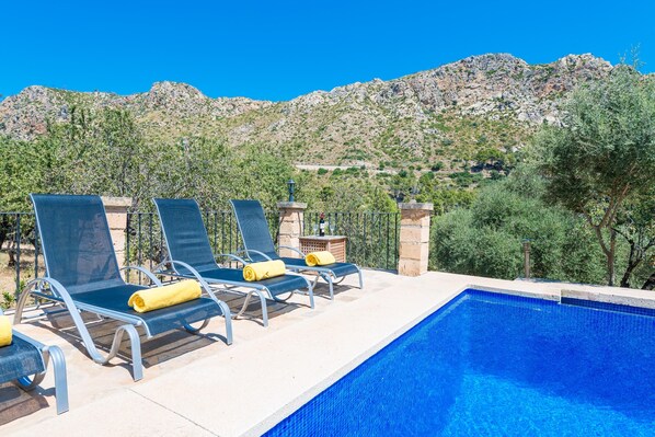 Zona de piscina con sillones de descanso y vistas a un paisaje montañoso.