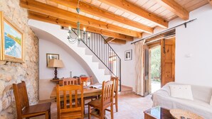 A cozy living area with a wooden staircase, a dining table with chairs, a sofa, and a coffee table. - SA TARONGERA - Villa with private pool in ANDRATX. Free WiFi (Andratx)