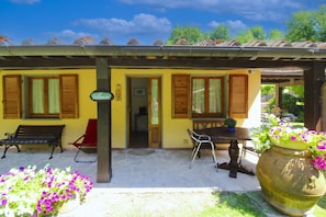 A yellow building with a tiled roof, wooden shutters, and a sign that reads 'Il Culipane'. There are two outdoor seating areas with chairs and a table, and a large flower pot with purple flowers. - Beautiful apartment for 6 people with WIFI and pets allowed (Terranuova Bracciolini)