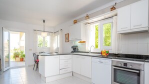Uma cozinha moderna com armários brancos, um forno Bosch e uma janela com cortinas.