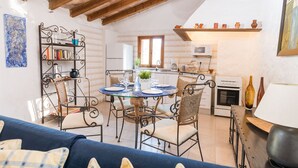A cozy dining area with a round table, wicker chairs, and a blue sofa. A kitchen with a stove and microwave is visible in the background. - CAN CAPET - Villa with private pool in Andratx. Free WiFi (Andratx)