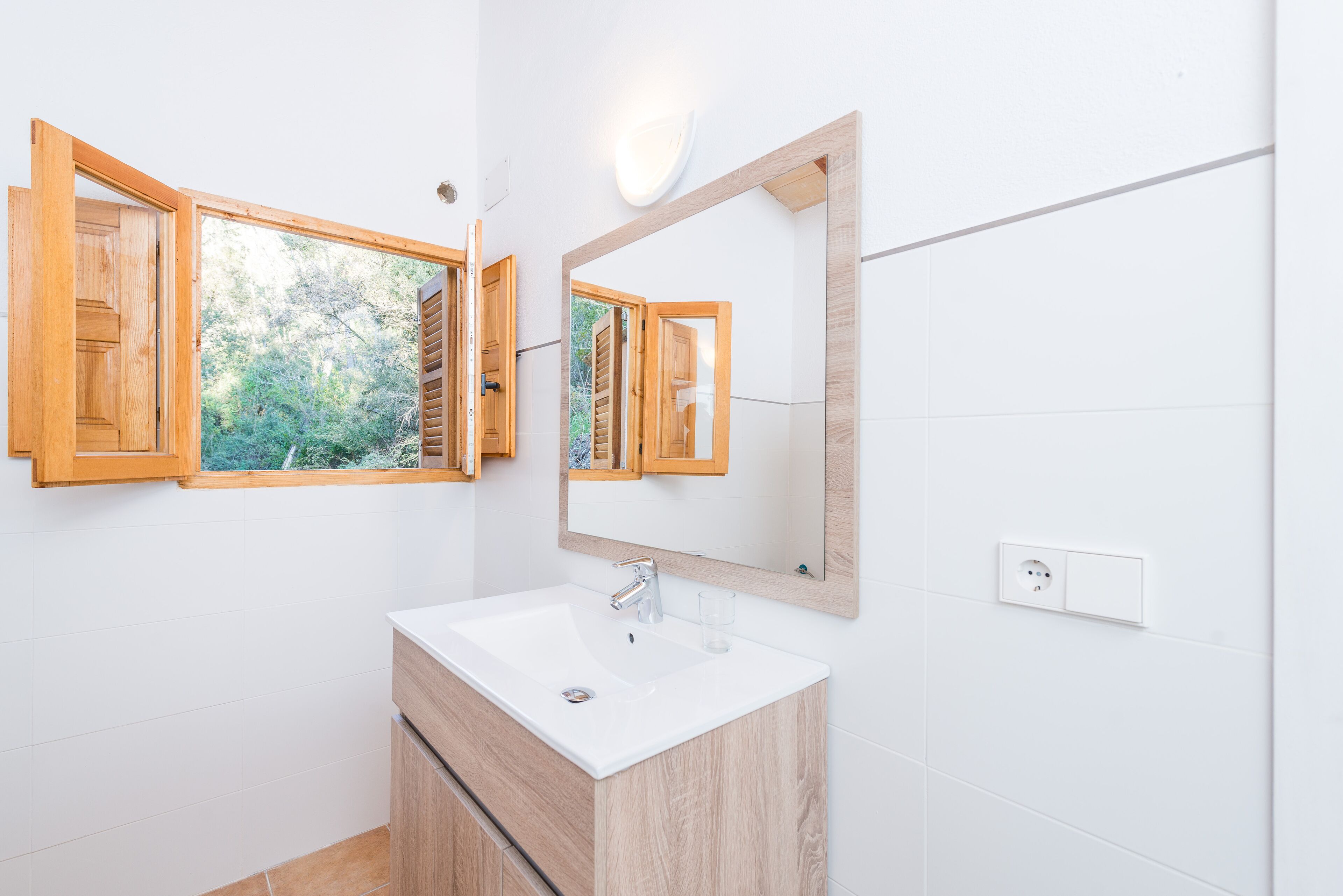 Une salle de bain moderne avec un meuble-lavabo en bois, un lavabo blanc et un grand miroir.