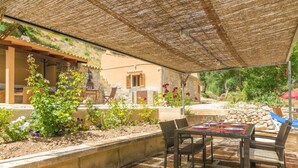 An outdoor patio with a table and chairs, surrounded by plants and a building with a stone facade. - CAN CAPET - Villa with private pool in Andratx. Free WiFi (Andratx)