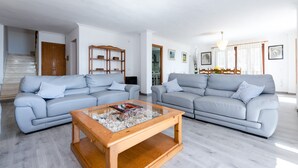 Una sala de estar moderna con dos sofás grises, una mesa de centro de madera y una escalera que conduce a otra habitación.