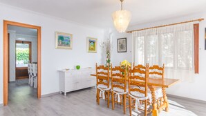 Un comedor con una mesa y sillas de madera, un armario blanco y obras de arte enmarcadas en la pared.
