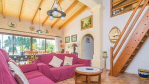 Ein gemütliches Wohnzimmer mit einem rosa Sofa, Holzbalken an der Decke und einer Treppe.