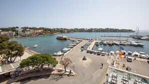 Un puerto deportivo con barcos amarrados, una carretera que lleva a un restaurante y edificios al fondo.
