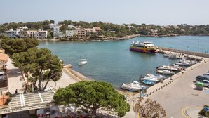 Un puerto deportivo con barcos amarrados, una zona de playa con sombrillas y edificios al fondo.