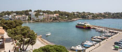 A marina with boats docked, a beach area with umbrellas, and buildings in the background.