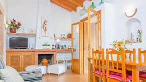 Una sala de estar acogedora con un sofá, una chimenea y un comedor con sillas de madera y una mesa.