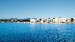 A coastal town with buildings along the waterfront, a clear blue sky, and boats in the water. - ES PORT  - Beautiful holiday home with private garden in Portocolom. Free WiFi (Portocolom)