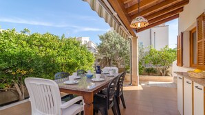 An outdoor dining area with a table set for four, surrounded by chairs, and a pergola overhead. - ES PORT  - Beautiful holiday home with private garden in Portocolom. Free WiFi (Portocolom)