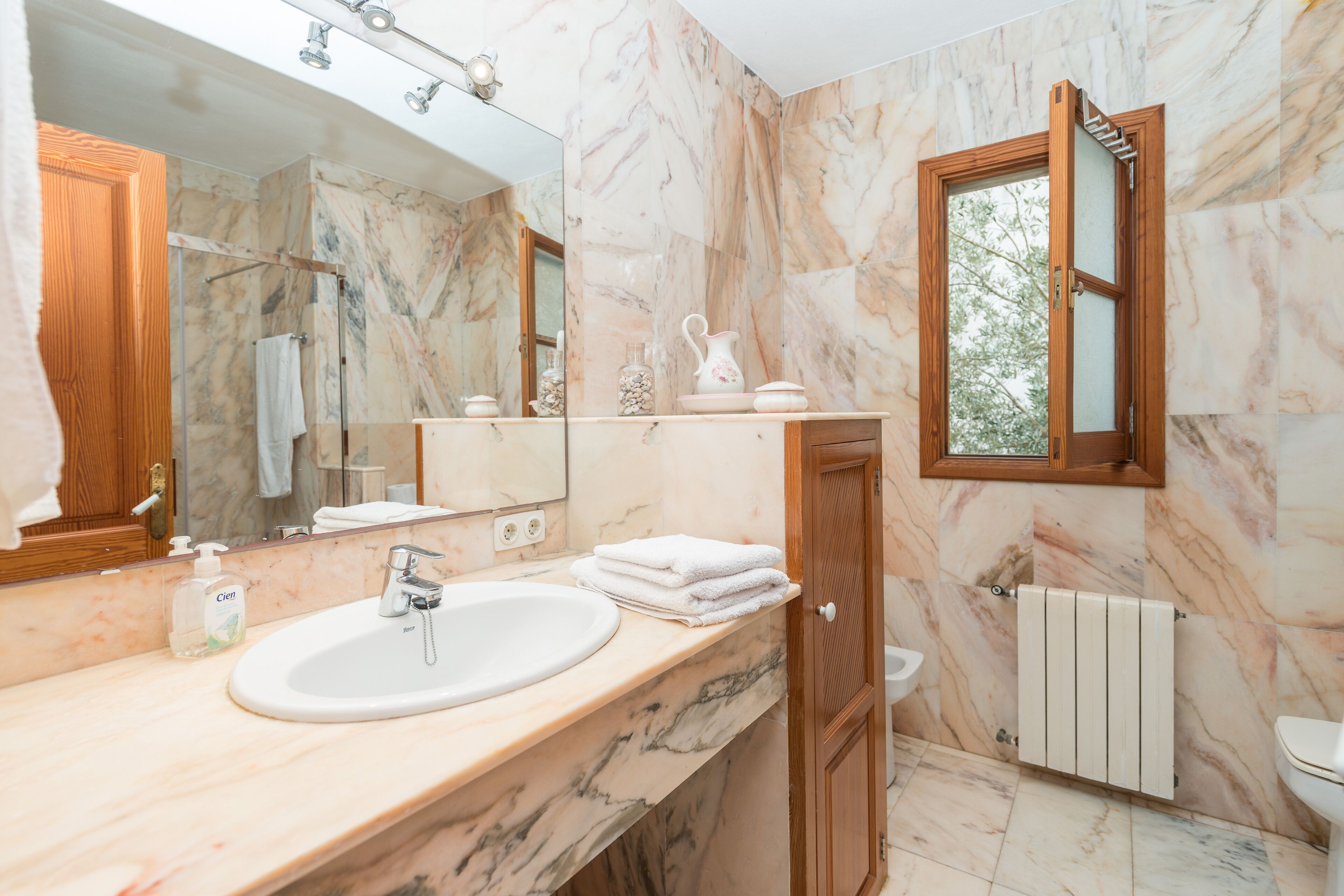 A bathroom with a marble sink, a mirror, a wooden door, and a window.