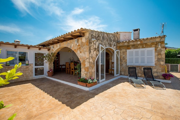 A stone house with a covered patio, outdoor seating, and a view of the surrounding landscape.