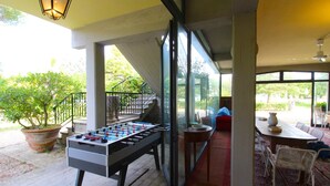 Una mesa de fútbol de mesa en un área exterior techada con patio, asientos y vistas al exterior.