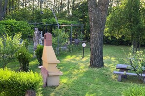 Een tuin met een stenen constructie, een boom en een bankje.