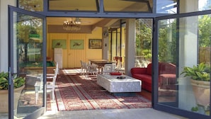 An open-plan living area with a dining table, chairs, a red sofa, and a marble coffee table.