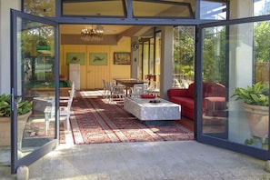 An open-plan living area with a dining table, chairs, a red sofa, and a marble coffee table.
