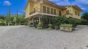 A two-story building with a balcony, surrounded by gravel and greenery.