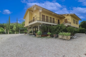 A two-story building with a balcony, surrounded by gravel and greenery.